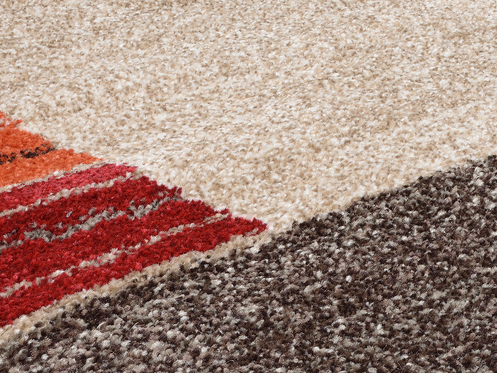 Nahaufnahme eines Frisé-Teppichs mit verschiedenen Farbbereichen in Beige, Rot, Orange und Braun.