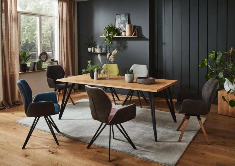 Esszimmer mit modernem Armlehnenstuhl in verschiedenen Farben um einen Holztisch, seitliche Perspektive