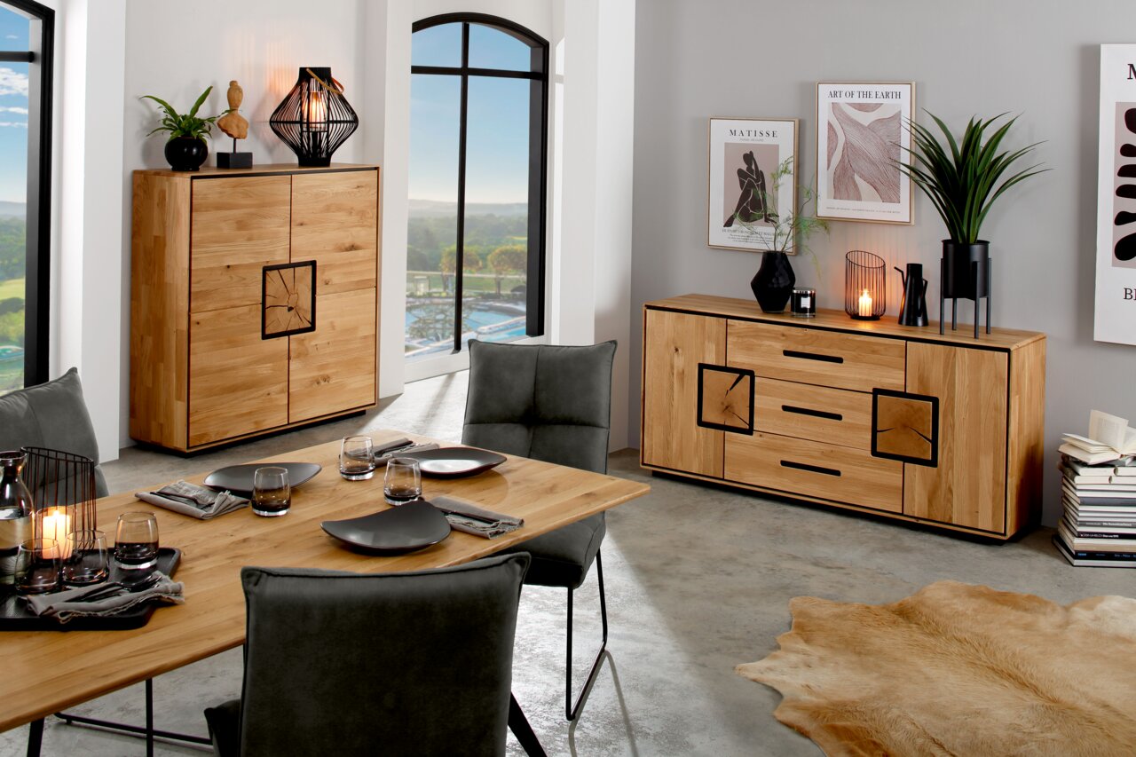 Landscape Highboard III BRIXEN Moderne eetkamer met dressoir en hoogkast van licht massief hout met zwarte accenten, gefotografeerd vanuit een schuin vooraanzicht in de ruimte.