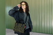 Frau mit Sonnenbrille trägt eine kleine Tasche mit Leopardenmuster, seitliche Perspektive