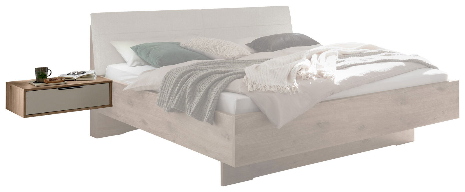 Modernes Holzbett in heller Eichenoptik mit gepolstertem, hellgrauem Kopfteil und schwebendem Nachttisch mit Schublade, dekoriert mit Bettwäsche und Decken; Ansicht schräg von vorn links.