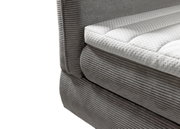 Nahaufnahme eines grauen Boxspringbetts mit gestepptem weißen Topper, seitliche Perspektive