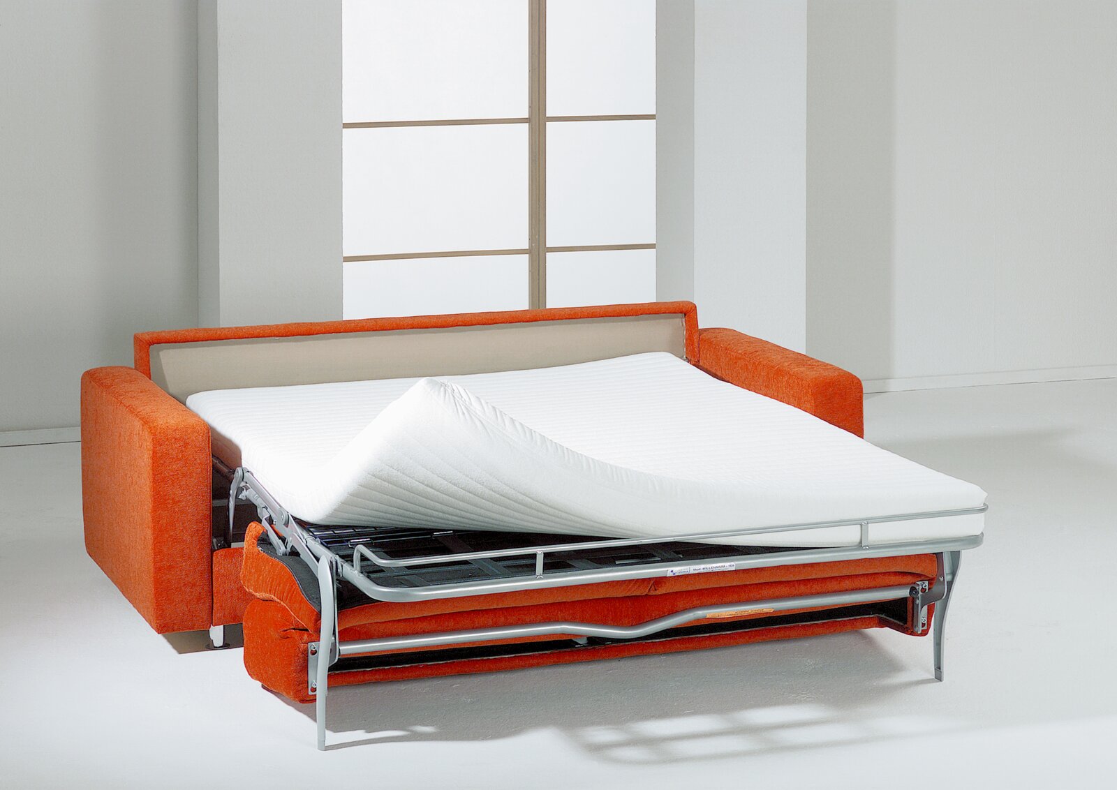 Orangefarbenes Schlafsofa mit ausgeklapptem Metallgestell und weißer Matratze, aus leicht erhöhter Frontansicht gezeigt