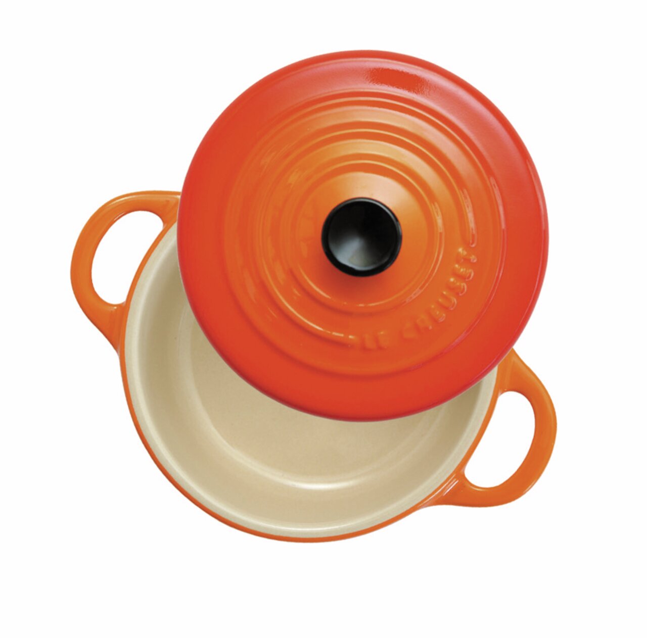 Bovenaanzicht van een mini-cocotte in ovenrood, met het deksel eraf en twee handvatten.