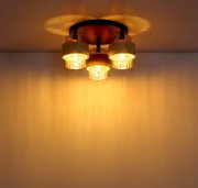 Plafondlamp met drie warm oplichtende glazen cilinders en een ronde metalen voet, gezien van onderaf (onderzicht)