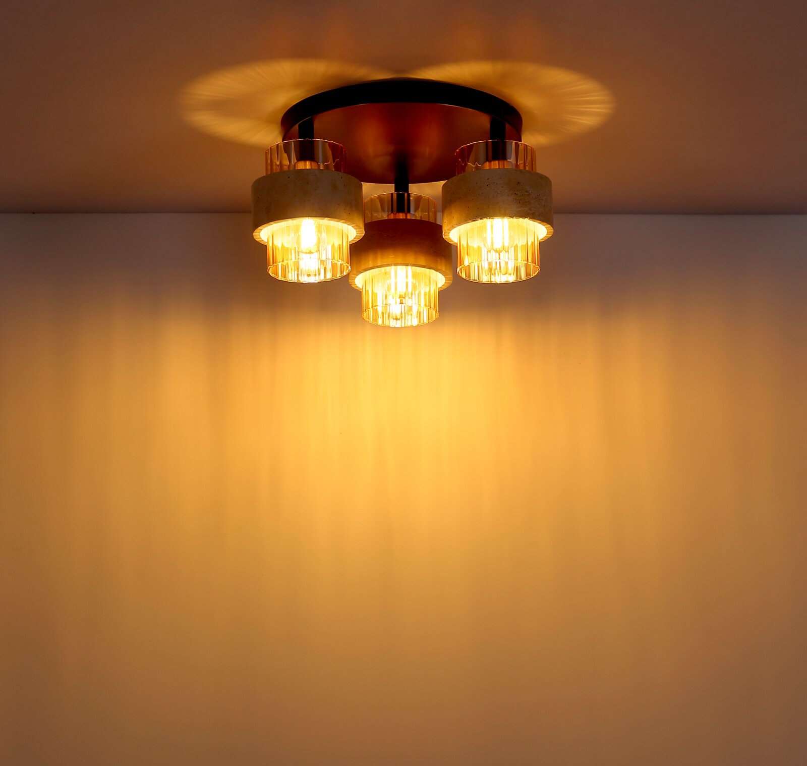 Plafondlamp met drie warm oplichtende glazen cilinders en een ronde metalen voet, gezien van onderaf (onderzicht)