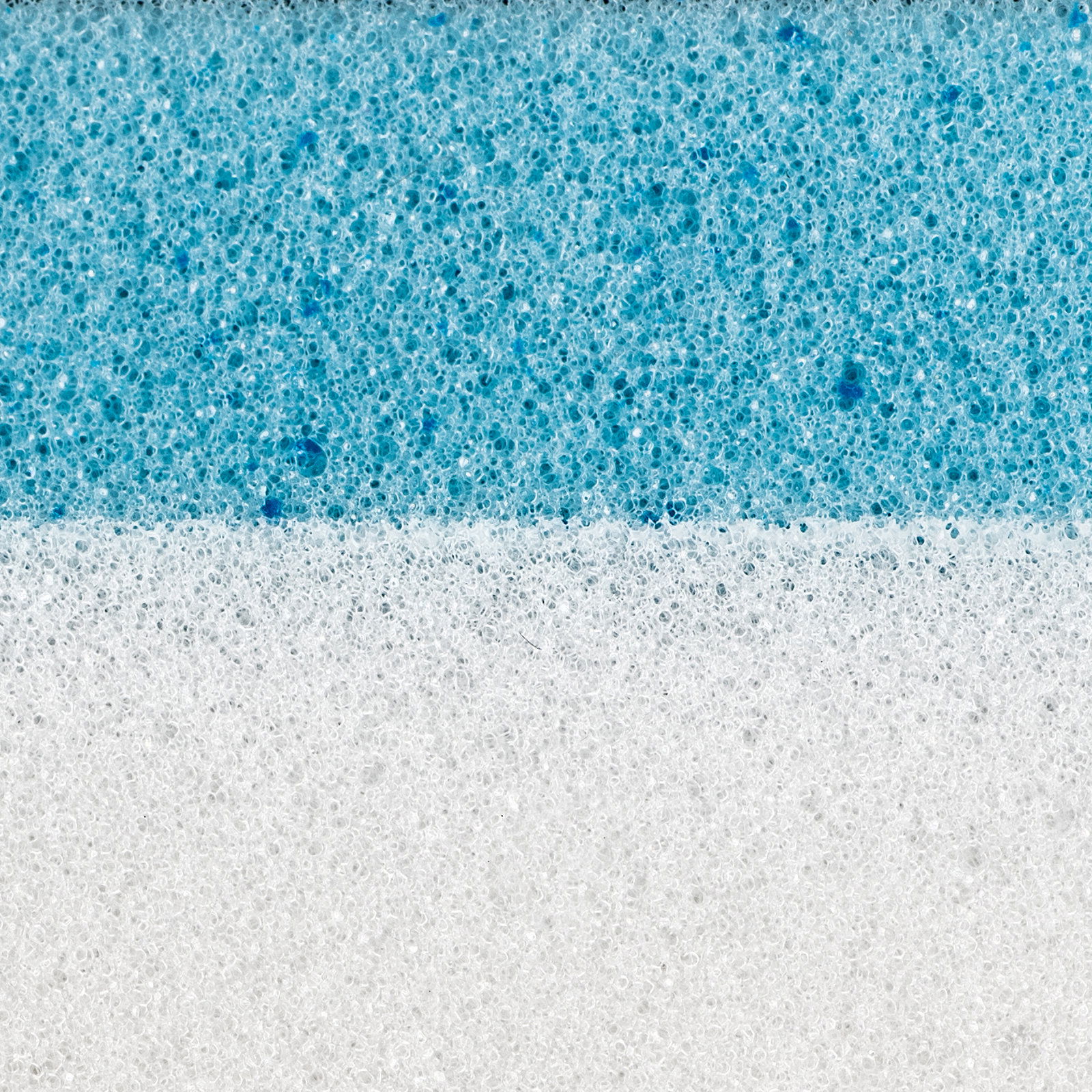 Nahaufnahme eines zweischichtigen Matratzentoppers mit einer weißen und einer blauen Schicht, die die Struktur und Textur des Materials zeigt.