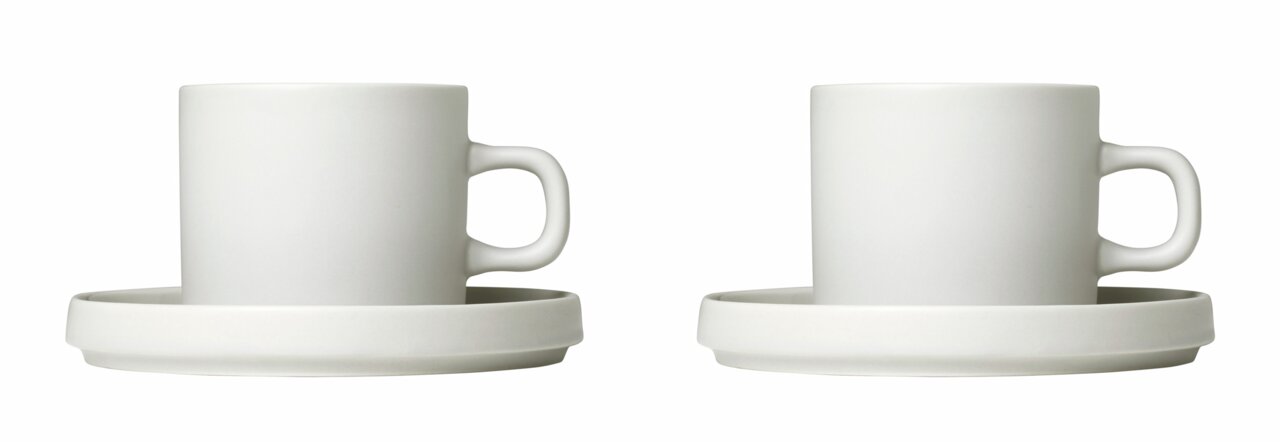 Zwei weiße Kaffeetassen mit Untertassen, frontal fotografiert.