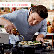 Mann gießt Öl in eine Pfanne auf einem Herd, seitliche Perspektive