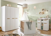 Helles Babyzimmer mit weißem Babybett mit Holzstäben, großem weißen Kleiderschrank und Wickelkommode mit Holzgriffen vor Wandmotiv mit Heißluftballons, frontal aus leicht seitlicher Perspektive aufgenommen.