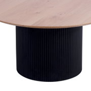 Runder Couchtisch mit heller Holzplatte und schwarzem, geripptem Zylindersockel, seitliche Perspektive