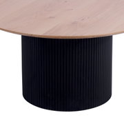 Ronde salontafel met een lichtgekleurd houten blad en een zwarte, geribbelde cilindervormige voet, gezien vanaf de zijkant