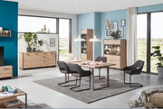 Moderne Esszimmermöbel in einem hellen Raum mit großen Fenstern, bestehend aus einem Esstisch mit vier Stühlen, einer Vitrine und einer Kommode, aus hellem Holz mit schwarzen Akzenten. Perspektive: Frontalansicht.