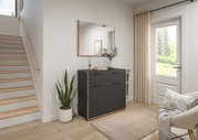 Moderne schwarze Kommode mit Holzrahmen und vier Türen im Flur, darüber ein rechteckiger Wandspiegel; seitliche Frontansicht in einem hellen Eingangsbereich neben Treppe und Fenster.