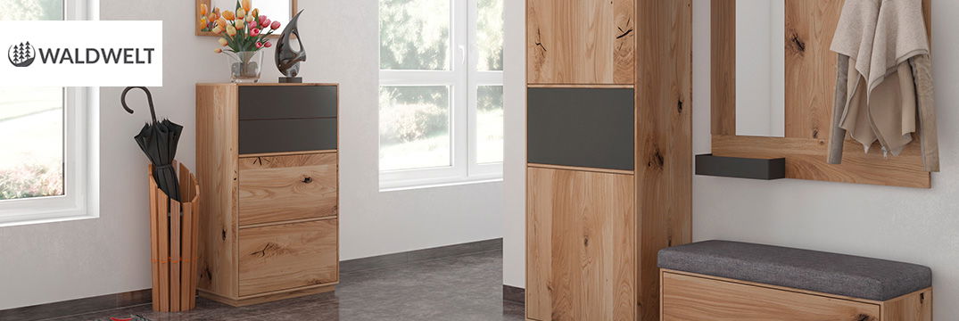 Ein heller Flur mit Holzmöbeln, grauer Sitzbank, Spiegel und einem Schirmständer vor großen Fenstern.