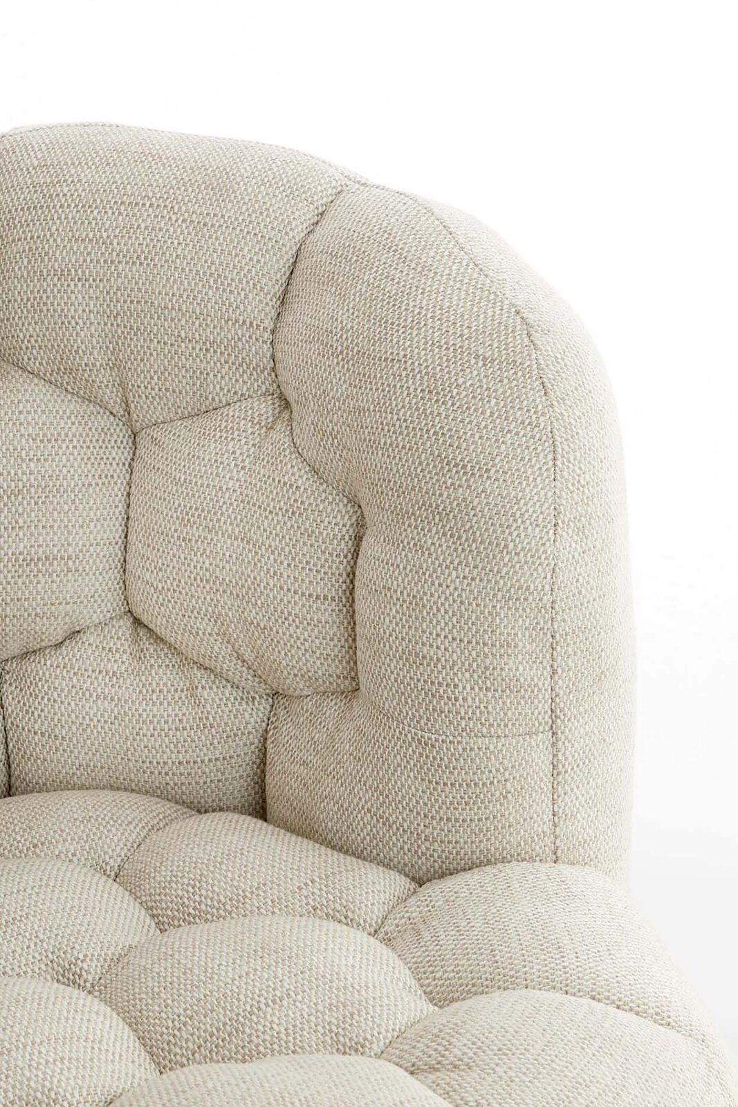Nahaufnahme einer beigen, gepolsterten Couch mit strukturierter Oberfläche und Knopfheftung, seitliche Perspektive