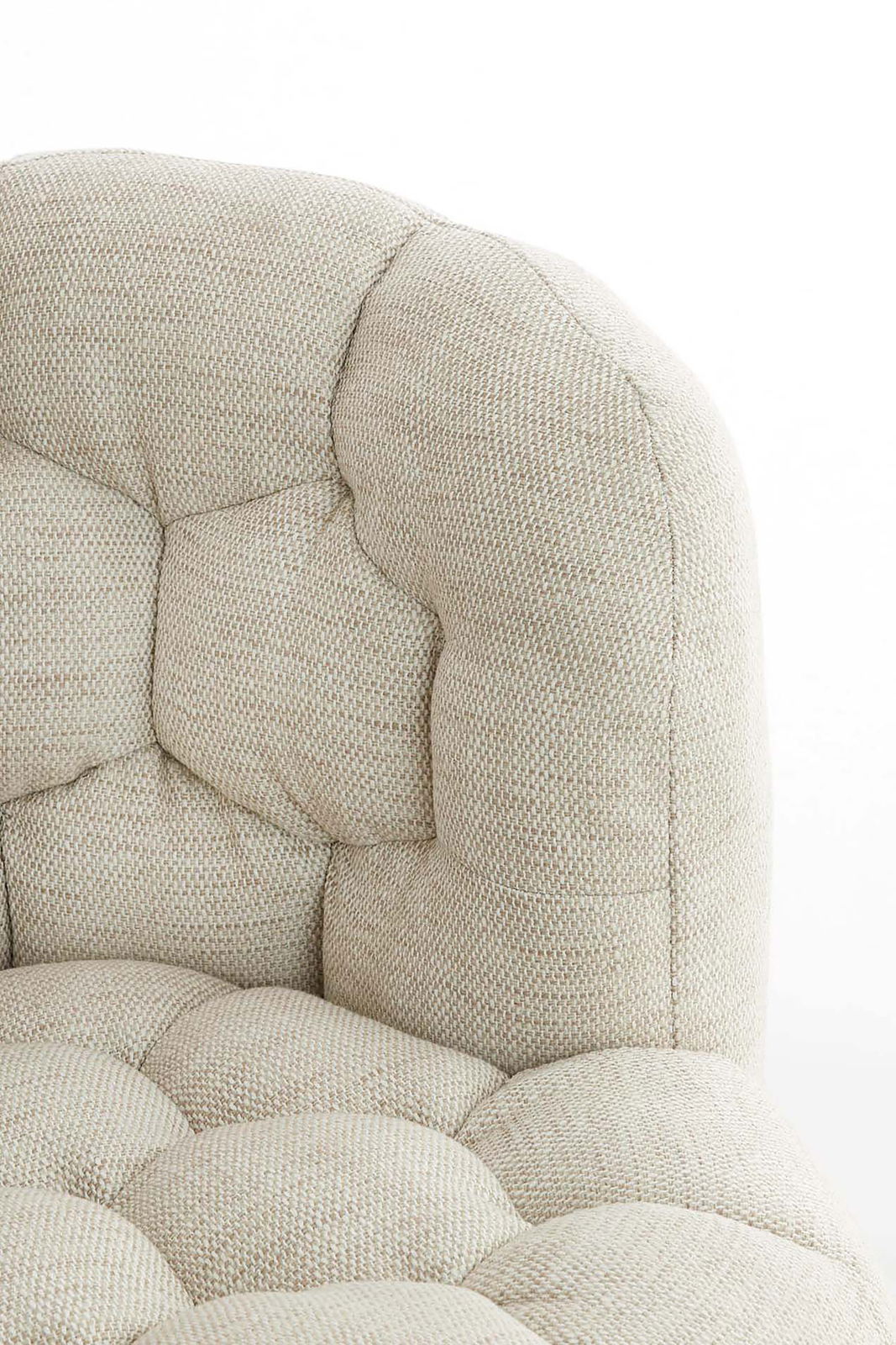 Nahaufnahme einer beigen, gepolsterten Couch mit strukturierter Oberfläche und Knopfheftung, seitliche Perspektive