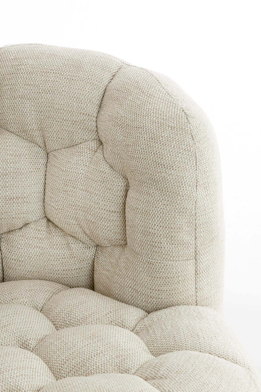 Nahaufnahme einer beigen, gepolsterten Couch mit strukturierter Oberfläche und Knopfheftung, seitliche Perspektive