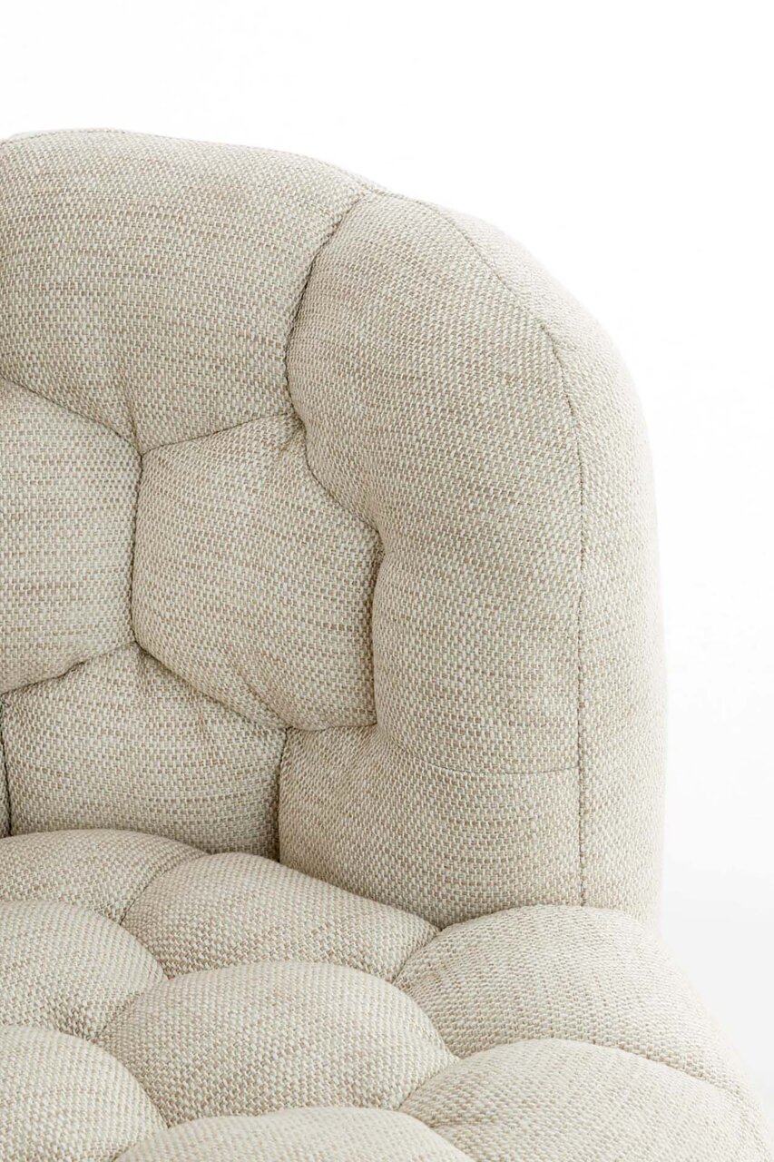 Nahaufnahme einer beigen, gepolsterten Couch mit strukturierter Oberfläche und Knopfheftung, seitliche Perspektive