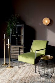 Highboard aus Metall mit Glastüren, dekoriert mit einer Pflanze, im Vordergrund ein grüner Sessel und ein Beistelltisch, seitliche Perspektive
