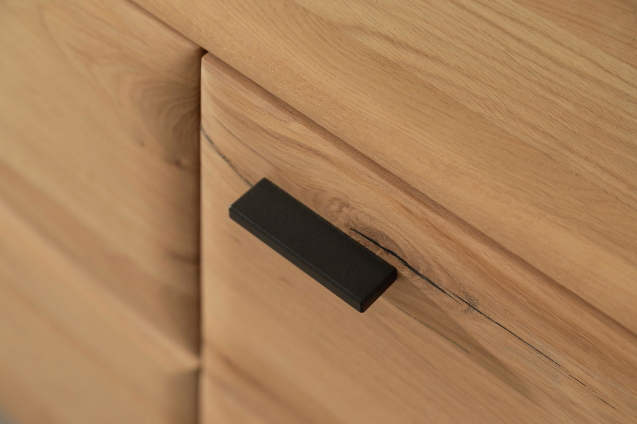 Nahaufnahme eines Holzschranks mit schwarzem Griff, Perspektive von schräg oben.