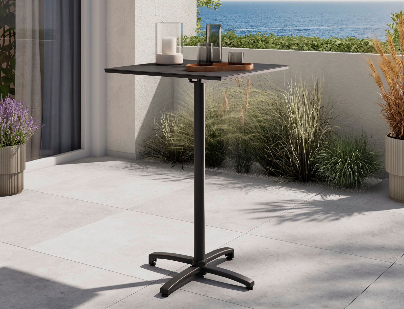 Moderner Stehtisch auf einer Terrasse mit Meerblick, dekoriert mit Kerzen und Pflanzen, seitliche Perspektive.