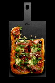 Schneidebrett mit Griff, darauf eine Pizza mit Schinken, Rucola und Oliven, aus der Vogelperspektive fotografiert.