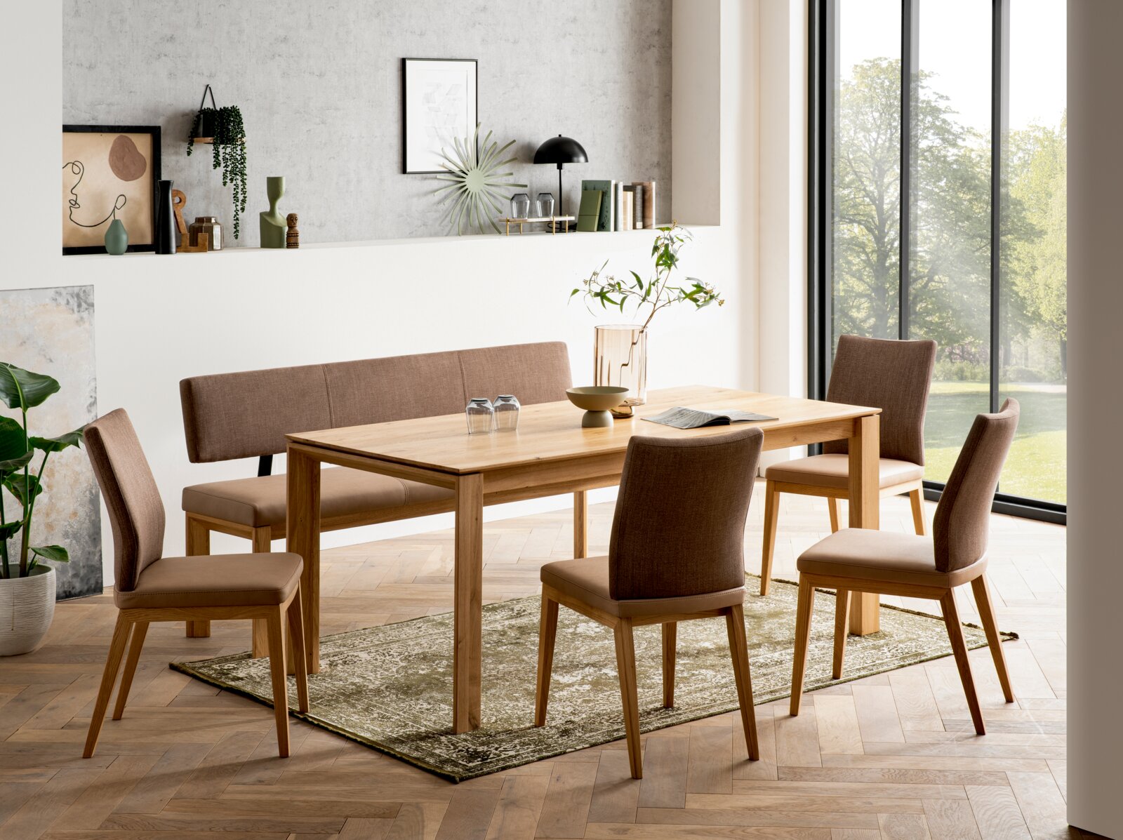 Modernes Esszimmer-Set mit rechteckigem Holzesstisch, gepolsterter Sitzbank und vier braunen Stühlen auf Teppich, fotografiert in leichter Schrägansicht von vorn.