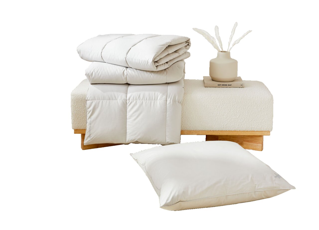 Perspektive auf ein gefaltetes weißes Steppbett und ein passendes Kissen, präsentiert auf einer modernen Bank mit Dekoration.