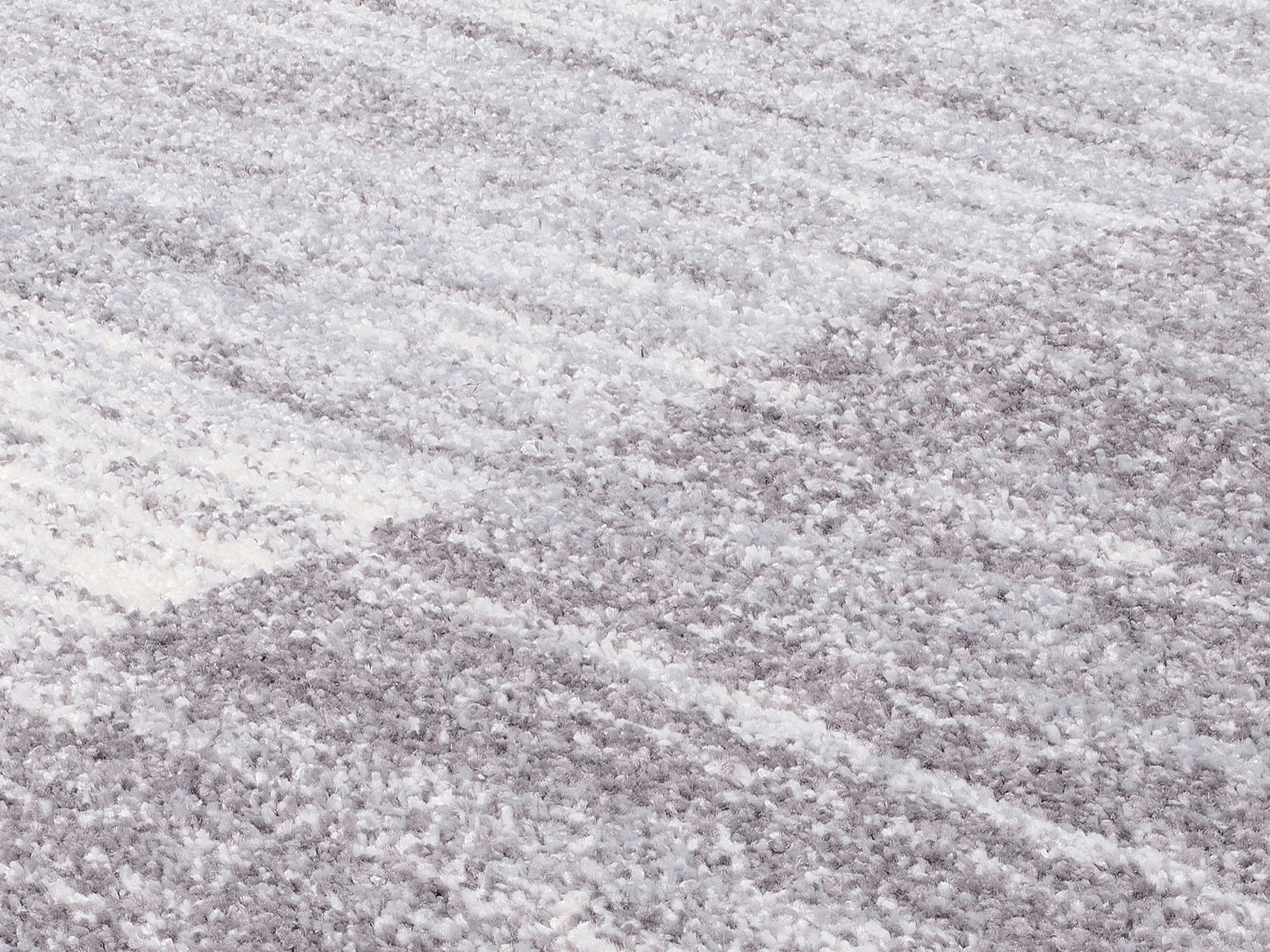 Nahaufnahme eines Frisé-Teppichs in Grautönen mit weicher, strukturierter Oberfläche.