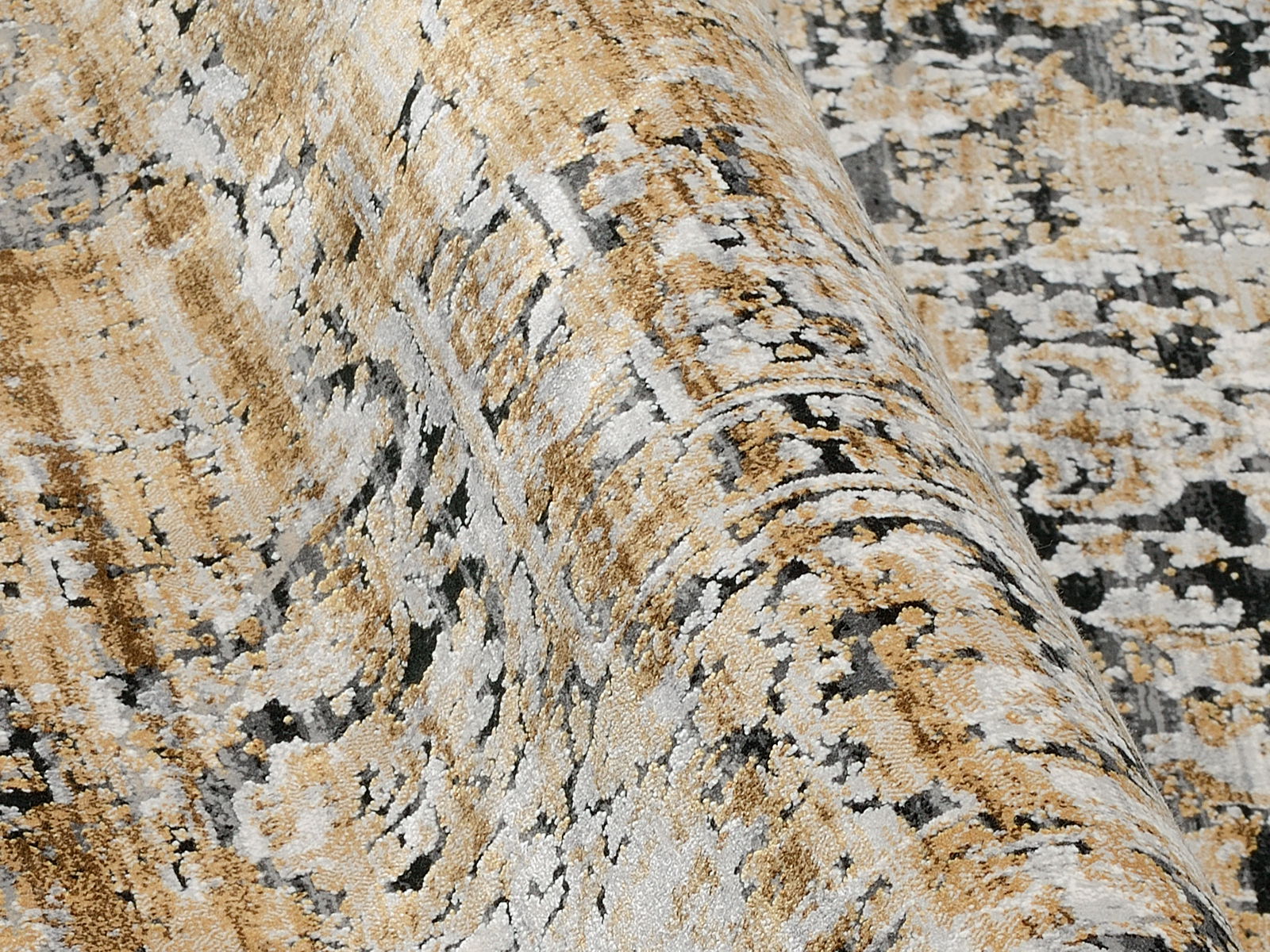Nahaufnahme eines Designer-Teppichs mit abstraktem Muster in Beige-, Grau- und Schwarztönen, aus seitlicher Perspektive aufgenommen.