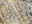 Nahaufnahme eines Designer-Teppichs mit abstraktem Muster in Beige-, Grau- und Schwarztönen, aus seitlicher Perspektive aufgenommen.