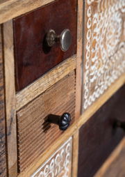 Nahaufnahme eines Sideboards mit verschiedenen Holzschubladen und dekorativen Knöpfen, seitliche Perspektive