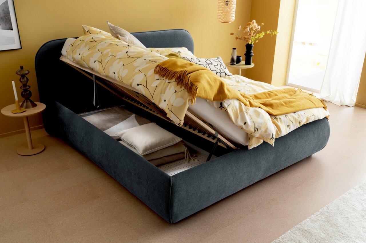 Polsterbett mit hochgeklappter Matratze und Stauraum darunter, seitliche Perspektive