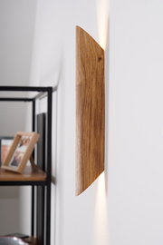 Seitliche Ansicht einer LED-Wandleuchte aus Holz mit warmem Lichtstrahl an einer weißen Wand.