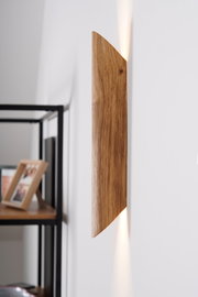 Seitliche Ansicht einer LED-Wandleuchte aus Holz mit warmem Lichtstrahl an einer weißen Wand.