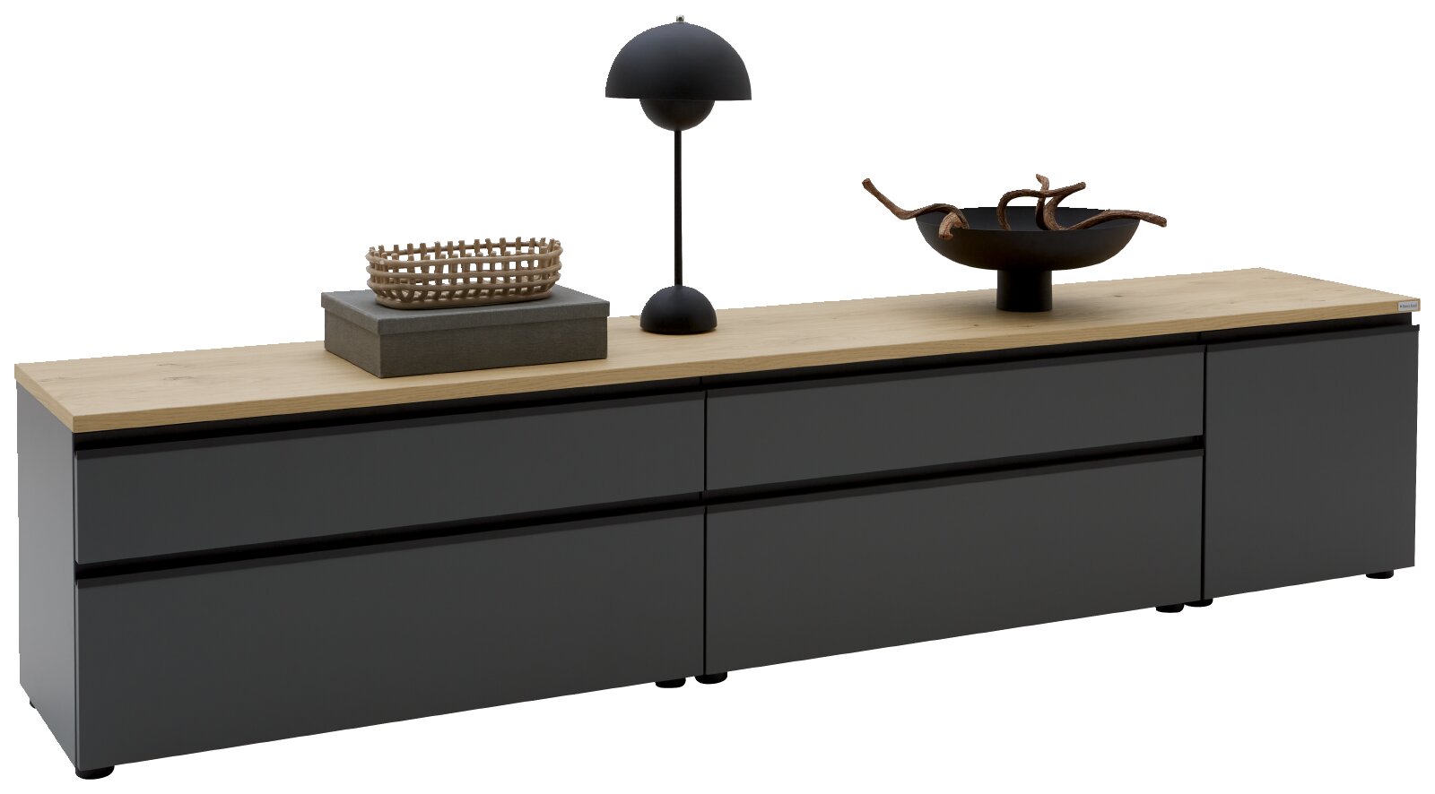 Modernes, niedriges Sideboard/TV-Board mit mattschwarzen Fronten und heller Holzplatte, dekoriert mit Lampe, Korb und Schale perspektivische Ansicht leicht von vorne rechts