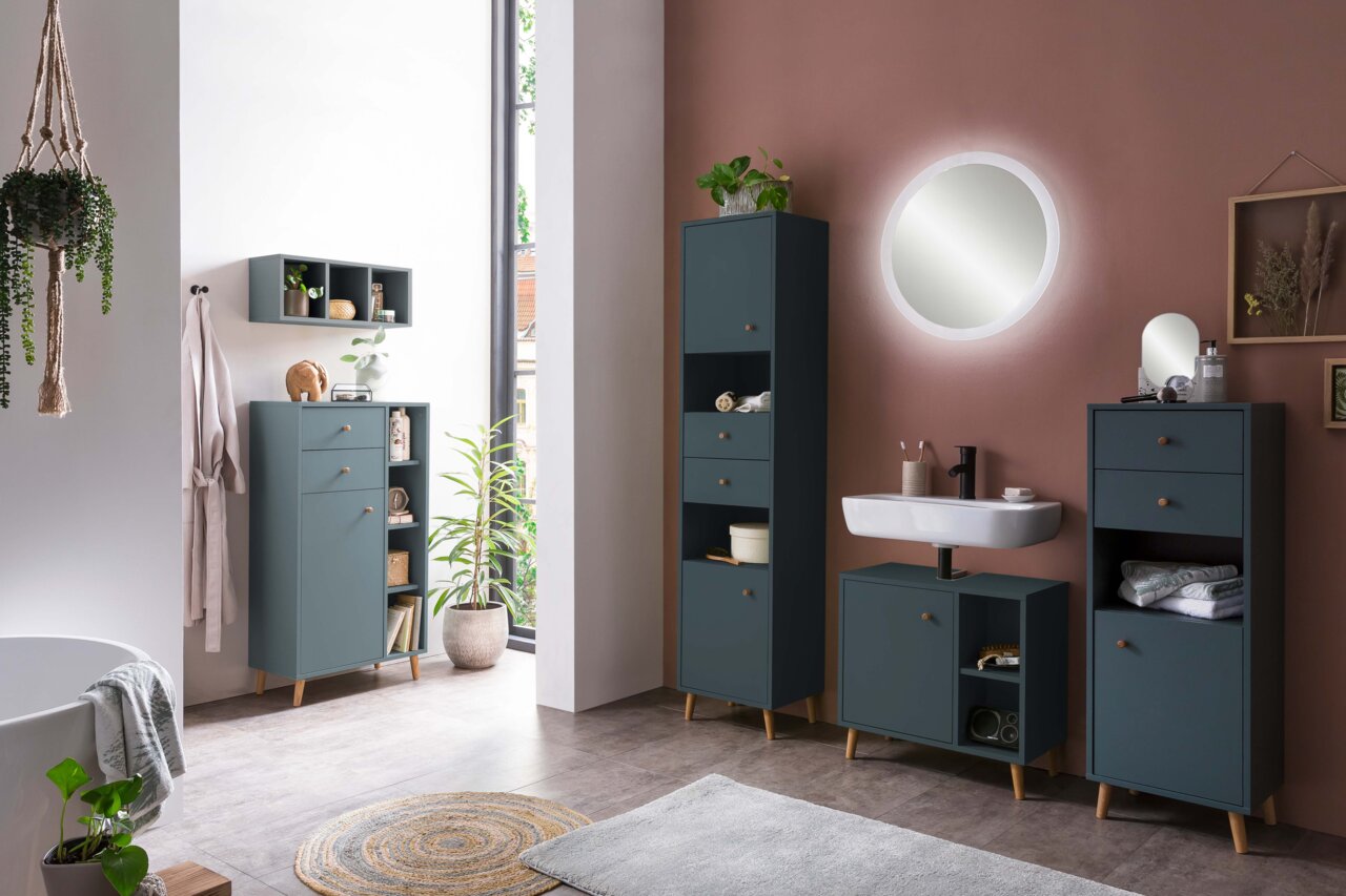 Moderner Badezimmer-Waschbeckenunterschrank in dunklem Blau mit Holzbeinen, frontal betrachtet, umgeben von passenden Schränken und Dekorationen in einem stilvollen Badezimmer.