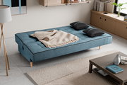 Schlafsofa 3 Sitzer in blauer Farbe, von oben fotografiert, mit zwei schwarzen Kissen und einer beigen Decke.
