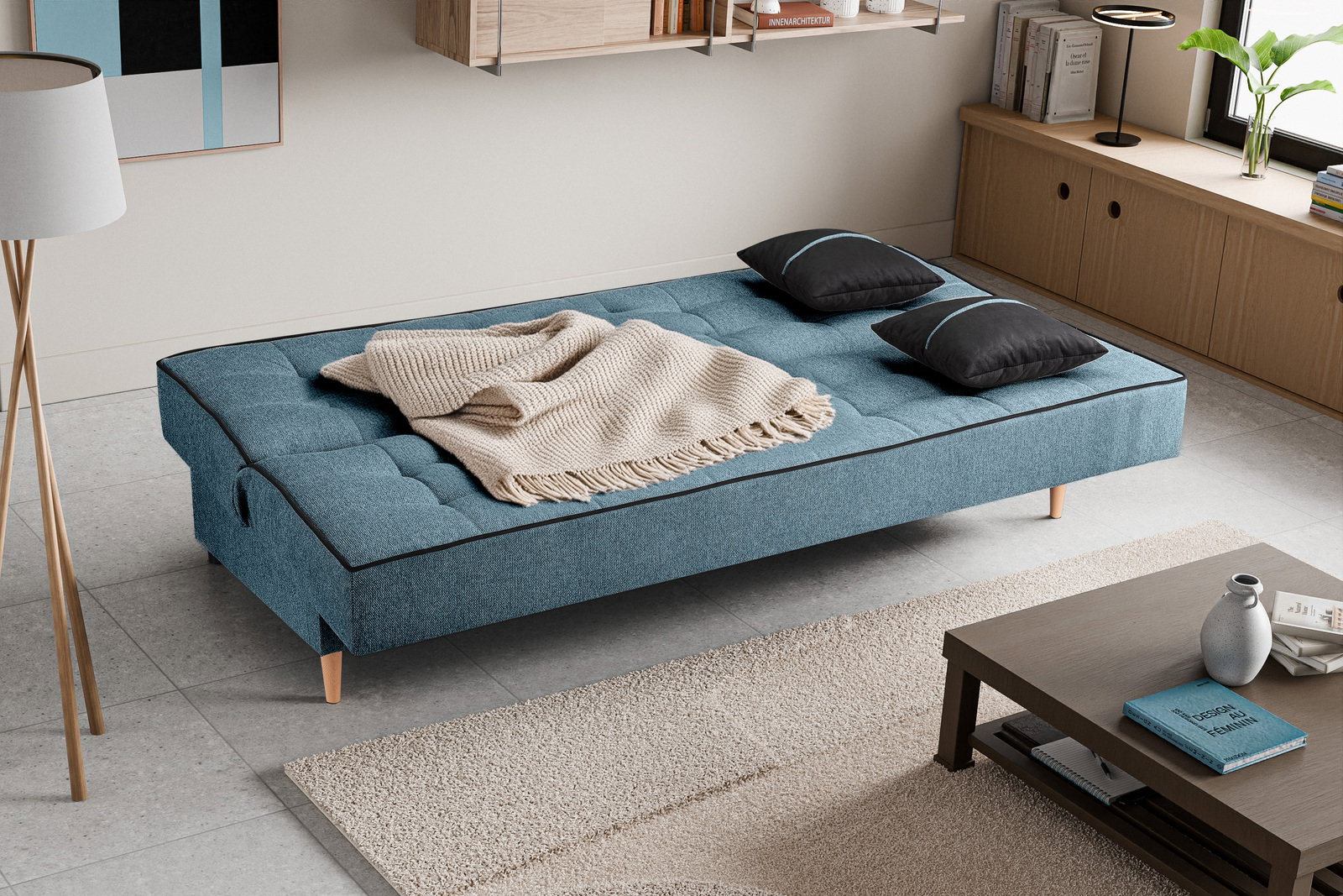 Schlafsofa 3 Sitzer in blauer Farbe, von oben fotografiert, mit zwei schwarzen Kissen und einer beigen Decke.