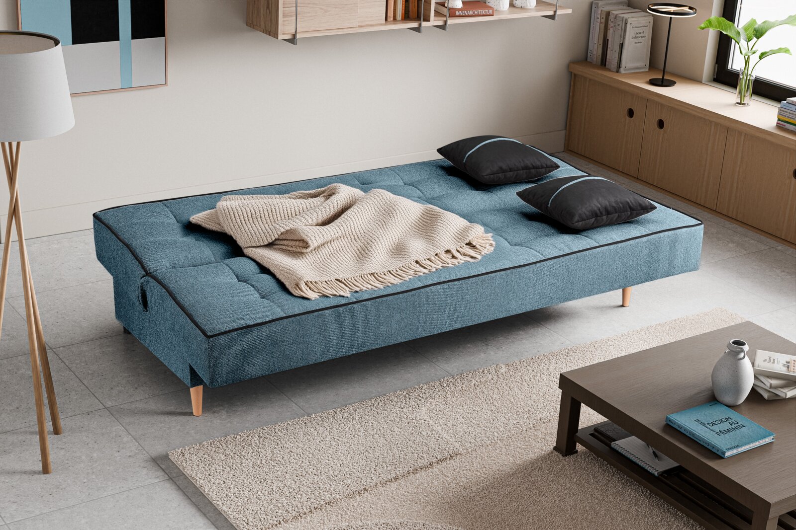 Schlafsofa 3 Sitzer in blauer Farbe, von oben fotografiert, mit zwei schwarzen Kissen und einer beigen Decke.