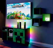 Minecraft-Gaming-Setup mit wandmontiertem TV, Creeper-Design-TV-Board und RGB-LED-Ambientebeleuchtung, frontal aus leicht schräger Perspektive von links aufgenommen.