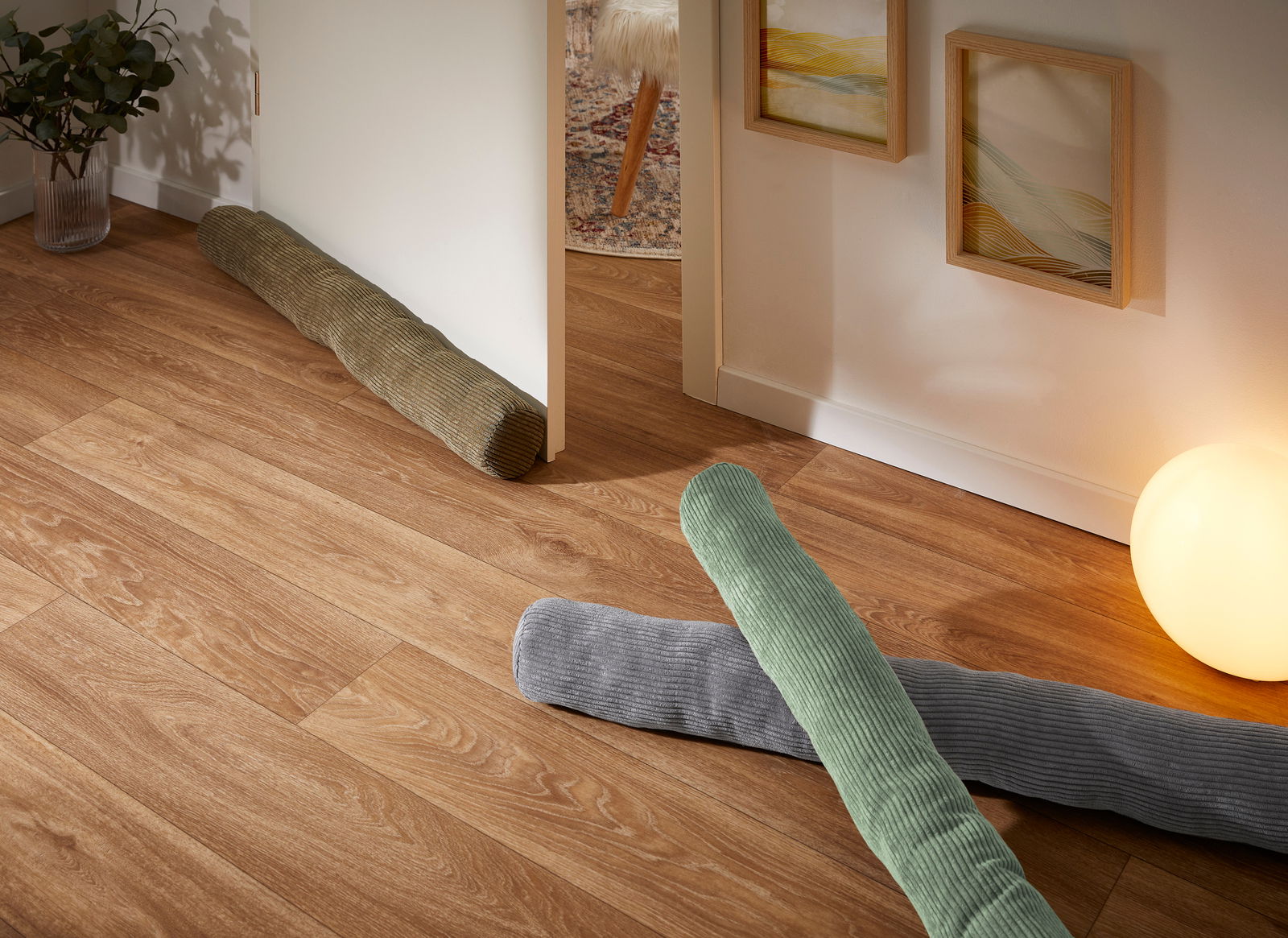 Andiamo 90 cm EMY Türstopper und Energiesparer Emy in verschiedenen Farben auf einem Holzfußboden, seitliche Perspektive.