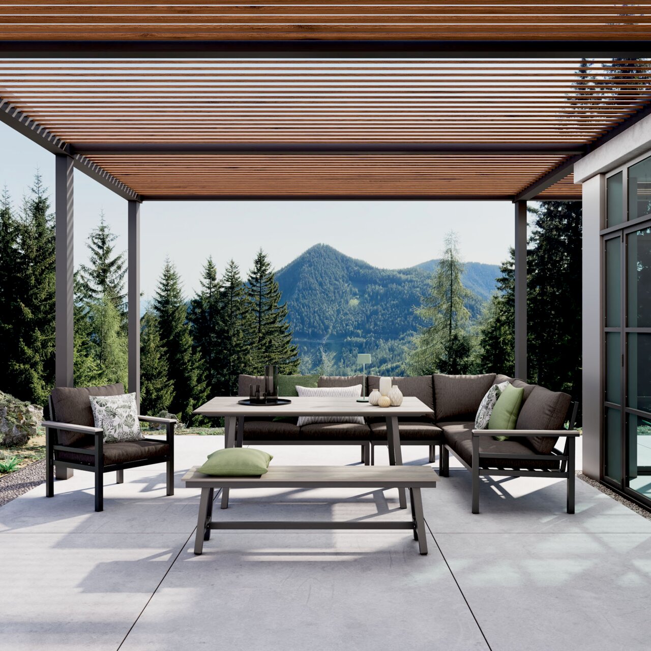 Moderne Outdoor-Lounge mit Ecksofa, Sessel, Esstisch und Bank unter Holz-Lamellen-Pergola auf Terrasse, frontal aus leicht niedriger Perspektive mit Berg- und Waldpanorama im Hintergrund
