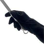 Close-up vanuit zijaanzicht: een hand met een zwarte beschermhandschoen houdt een keukenmes vast met een roestvrijstalen lemmet en een metalen handvat met ophangring