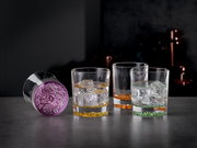 Vier Trinkbecher mit farbigen Böden in Lila, Gelb, Orange und Grün, gefüllt mit Eiswürfeln, auf einer dunklen Oberfläche. Perspektive: seitlich.