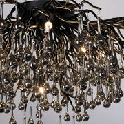 Nahaufnahme einer Deckenleuchte ICICLE mit hängenden, tropfenförmigen Glaselementen und glänzenden Metallstrukturen, von unten betrachtet.