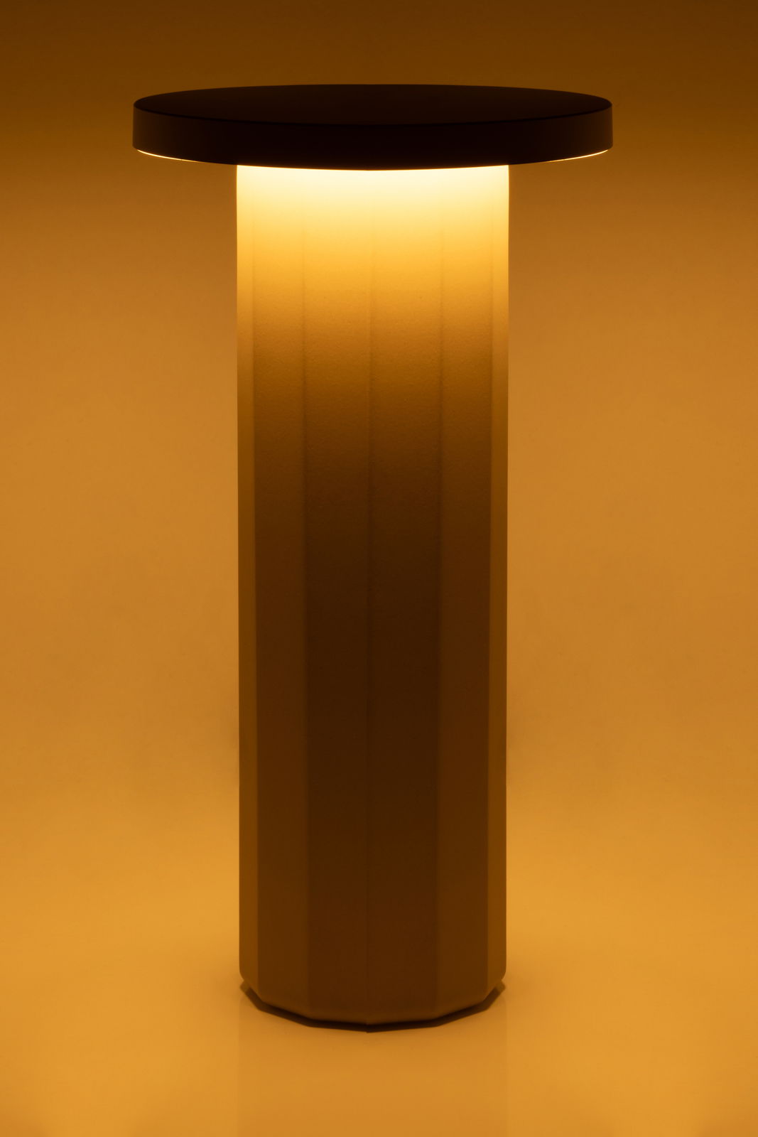 Akku-Tischleuchte mit zylindrischem Sockel und rundem, leuchtendem Schirm, seitliche Perspektive