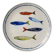 Runder cremefarbener Keramikteller mit blauem Rand und fünf farbenfrohen Fischmotiven, in der Draufsicht vor weißem Hintergrund