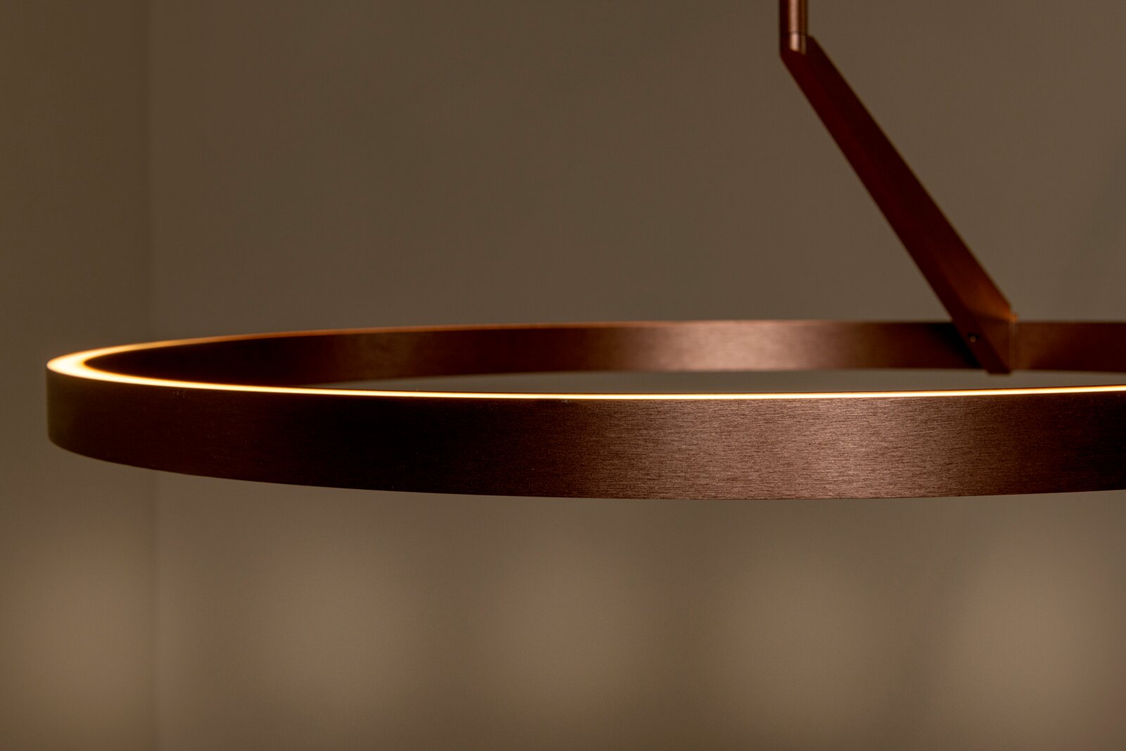 Nahaufnahme einer runden, ringförmigen LED-Pendelleuchte in gebürsteter Kupfer-/Bronzeoptik, seitliche Perspektive vor neutralem Hintergrund
